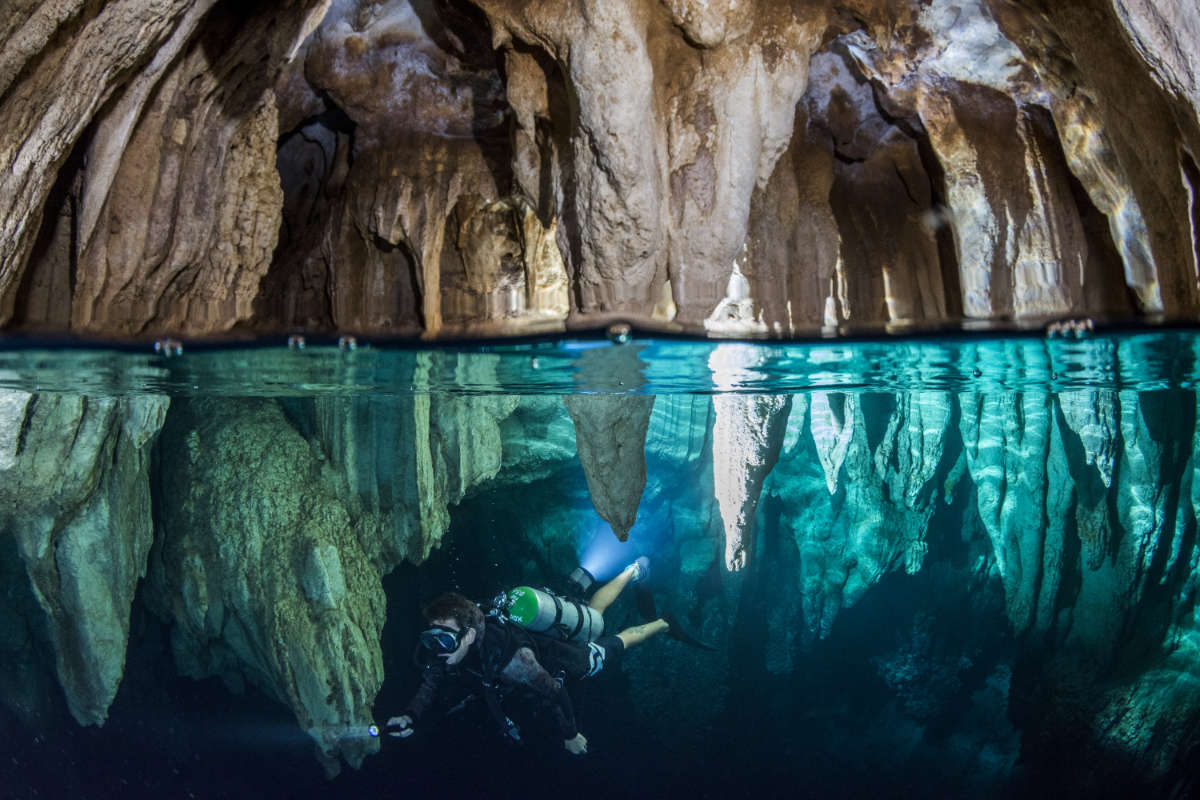 Split photo showing diver and cave - half underwater - half air pocket at the Chandelier Cave Palau