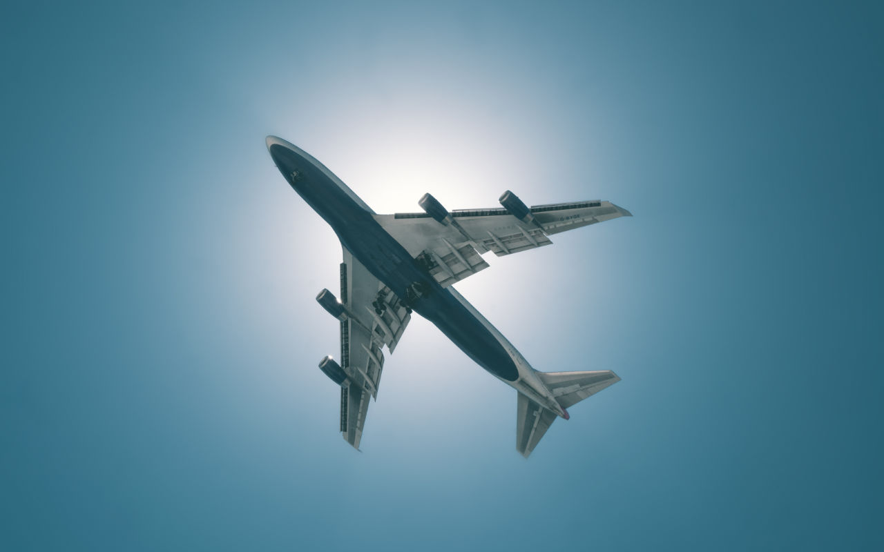 Commercial Airplane shot at start from underneath against the sun